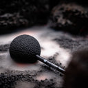 Gong Mallet der Lava Edition mit schwarzem, strukturiertem Kopf auf dunklem Lavagestein
