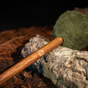 Gong Mallet der earthtones Serie mit moosgrünem Kopf und dunklem Holzgriff auf Waldboden mit Rinde