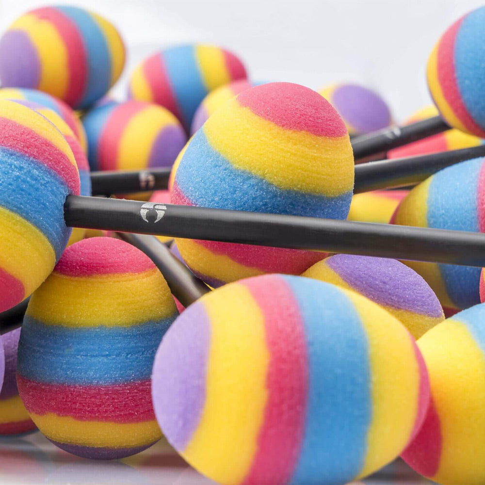 Many Crazy Egg gong beaters with rainbow-colored foam heads, arranged closely together